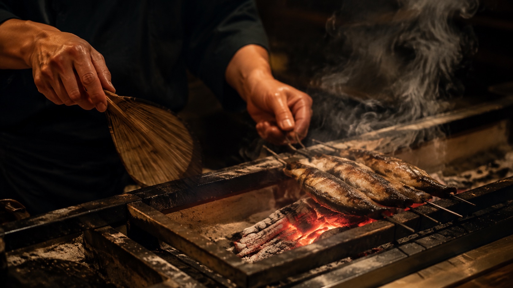 炭火の上で魚を焼く料理人の手元